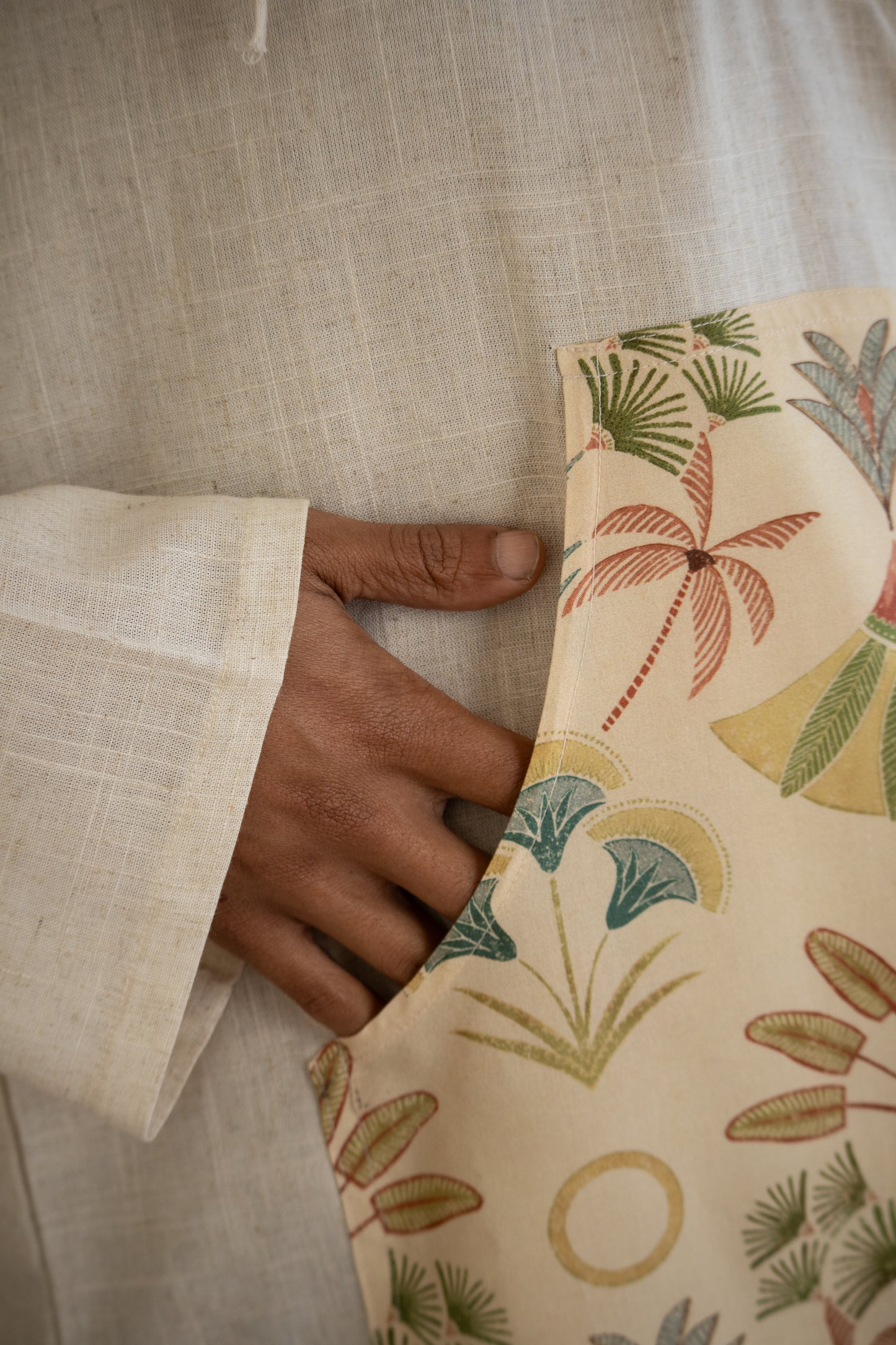 Hand holding a patterned pouch with palm tree design on a textured fabric background