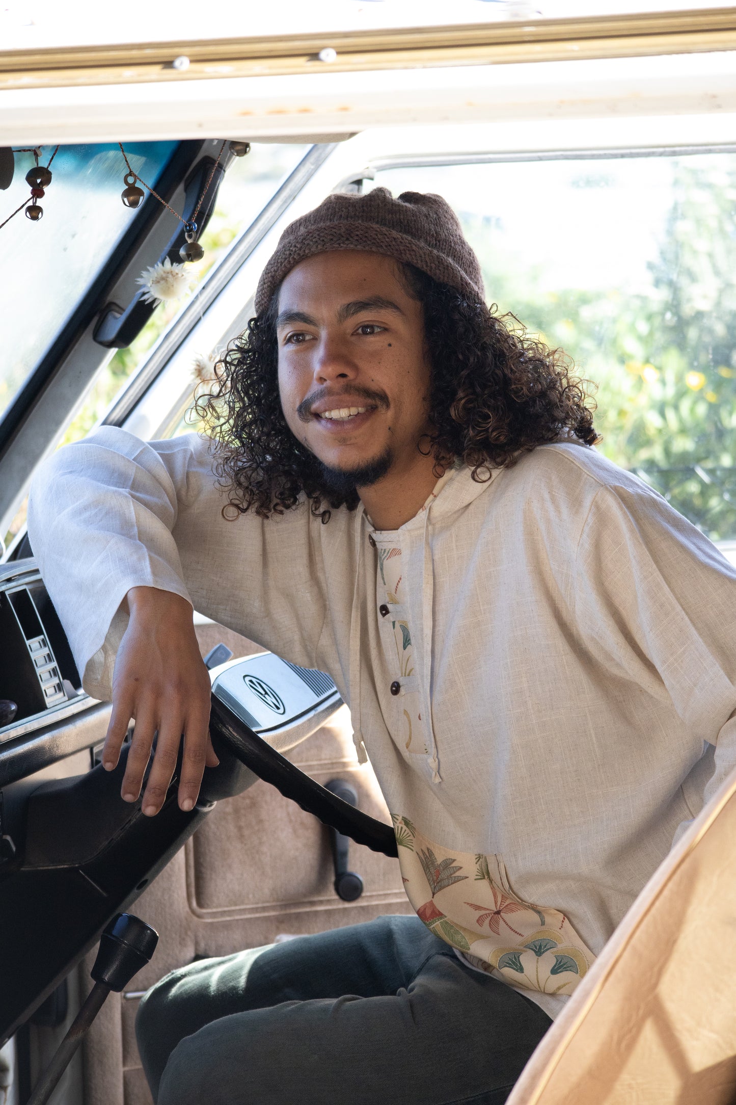 Man sitting inside a vehicle wearing a light-colored shirt with floral patterns.