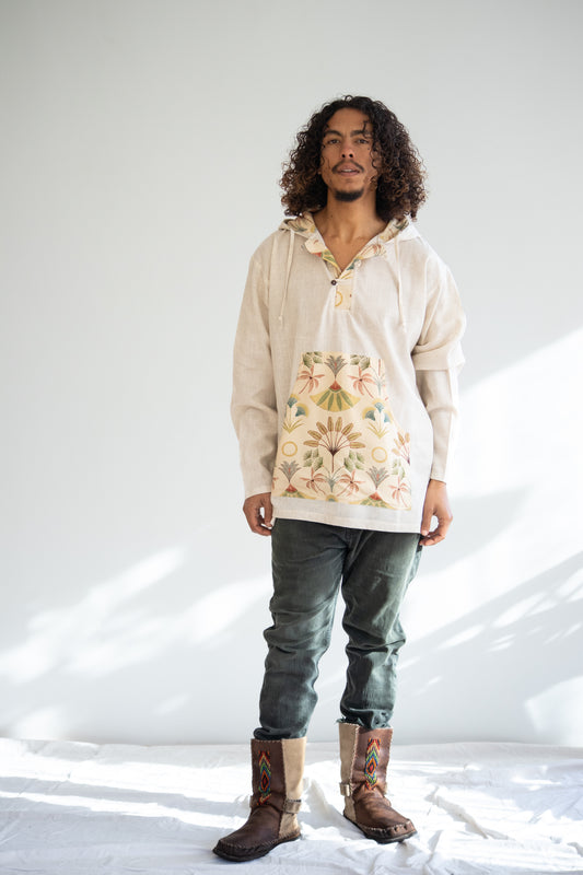 Man wearing a light-colored hoodie with a floral design, dark jeans, and brown boots on a white background